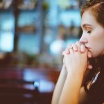 A girl puts her hands together in prayer